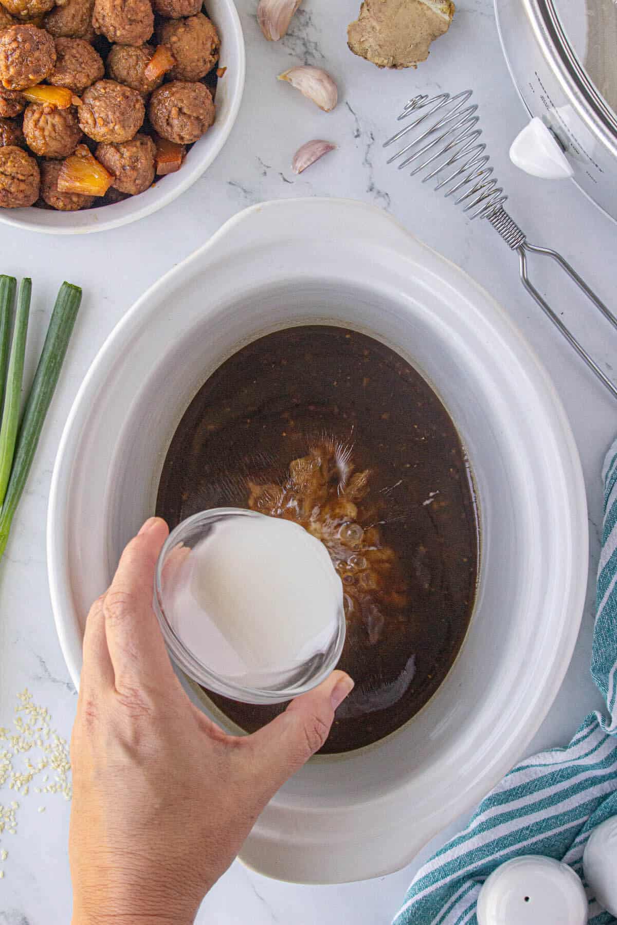 Cornstarch slurry poured into the crockpot to thicken the sauce.