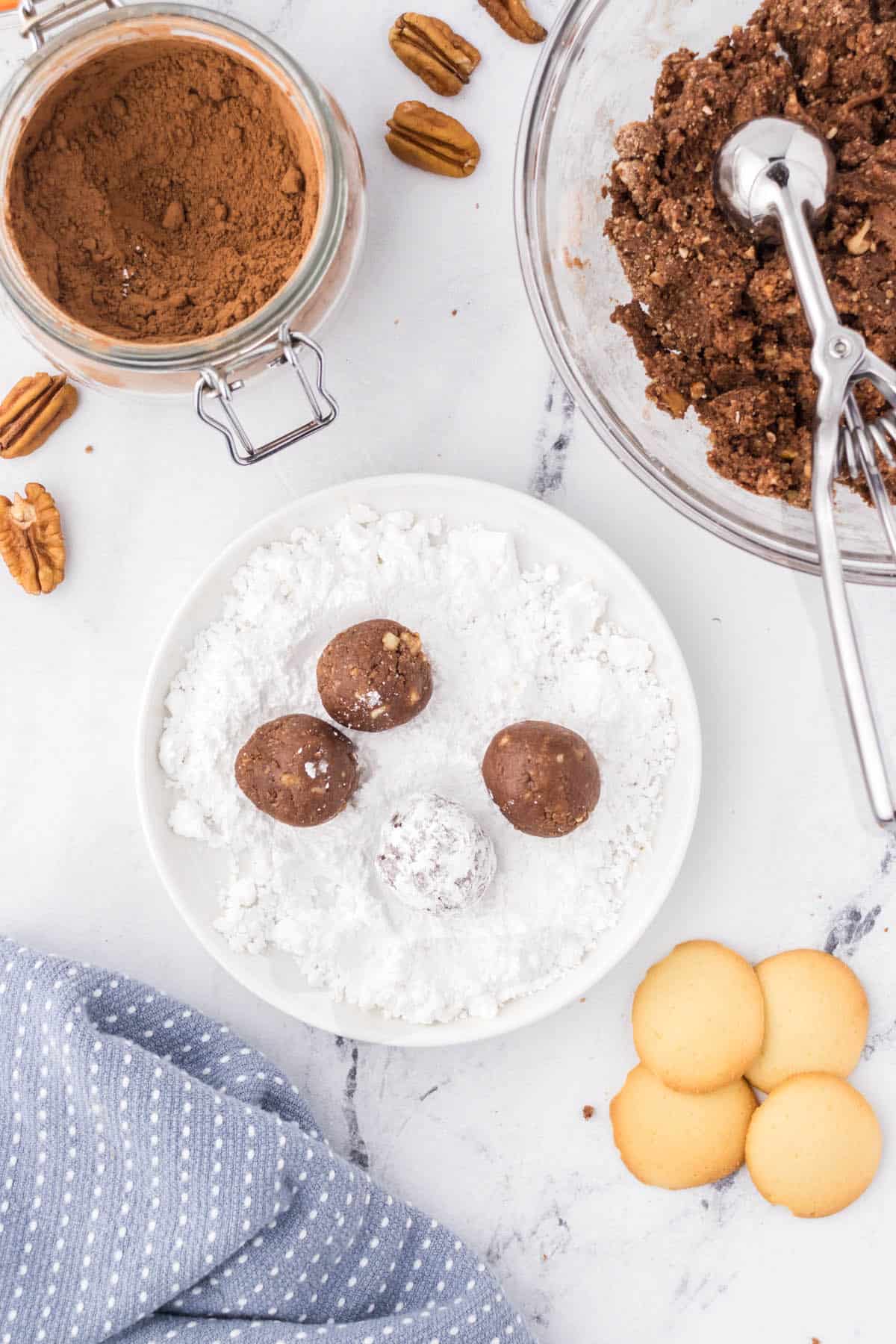 Bourbon balls being rolled in powdered sugar.