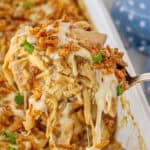 Cheesy French Onion Chicken and Rice Casserole in a baking dish with a serving spoon taking a scoop.