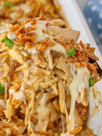 Cheesy French Onion Chicken and Rice Casserole in a baking dish with a serving spoon taking a scoop.