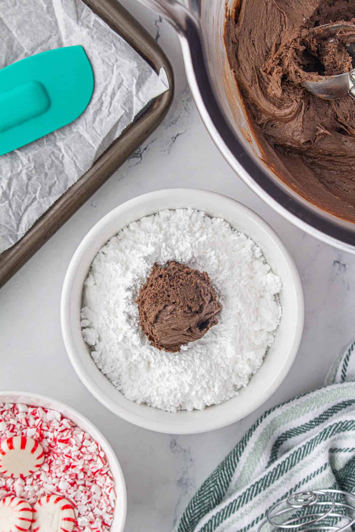 Cake mix cookie batter being rolled in a bowl of powdered sugar.