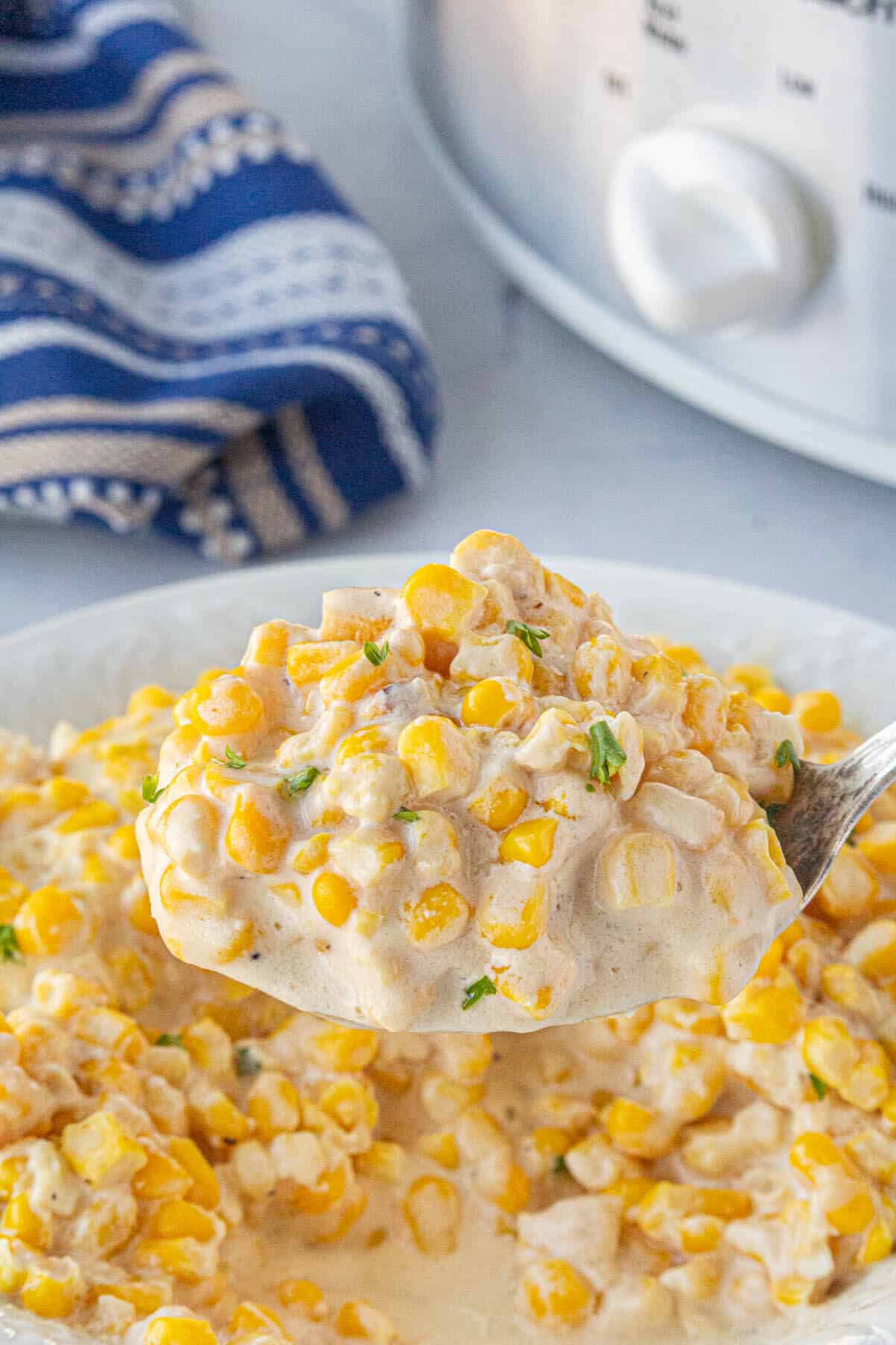 Crockpot Cream Corn in a bowl, with a serving spoon.