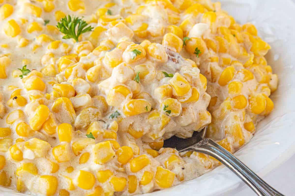 Creamed corn in a bowl with a serving spoon.