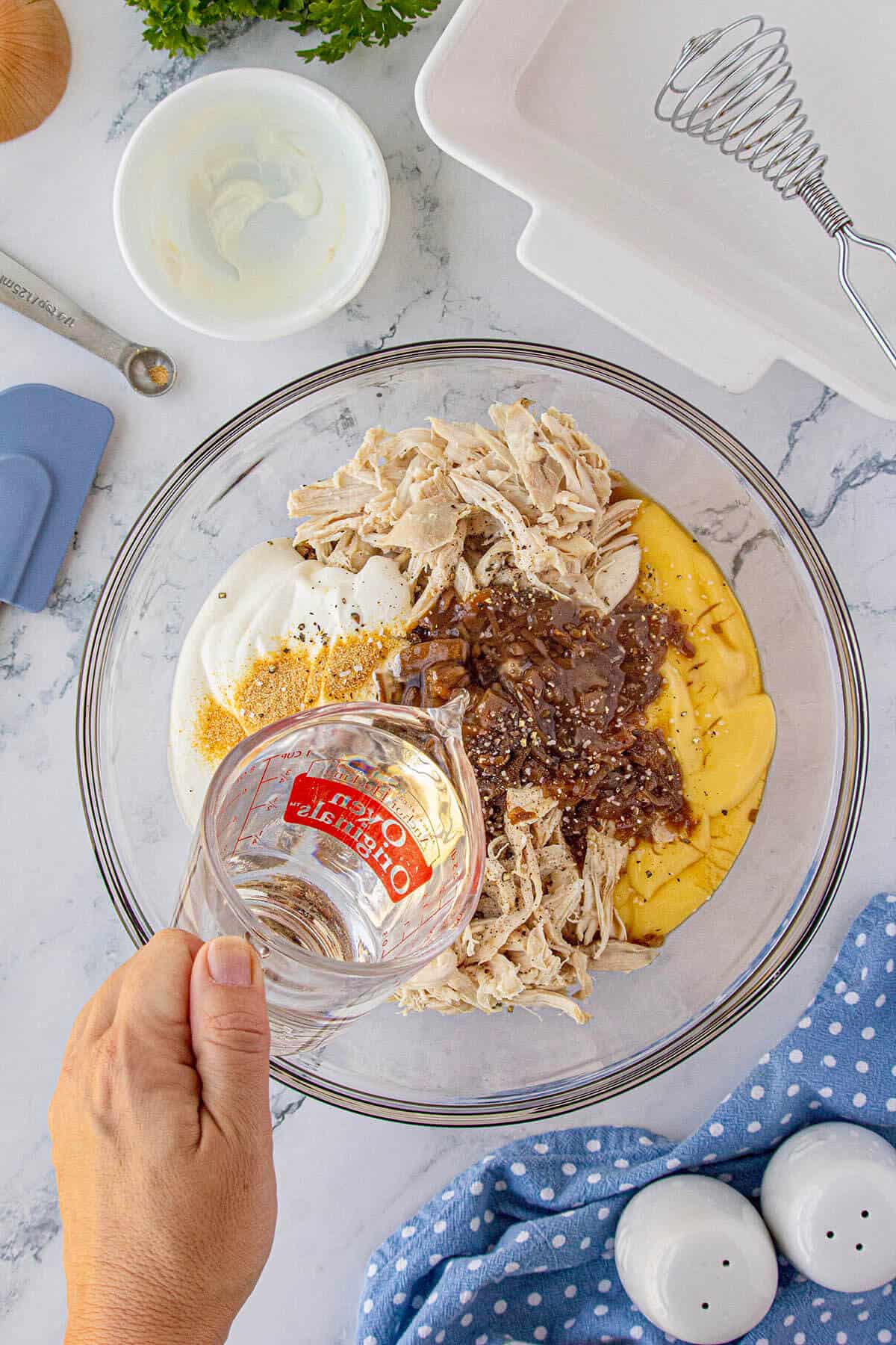 Chicken, canned soups, sour cream, and watering being combined in a large mixing bowl.