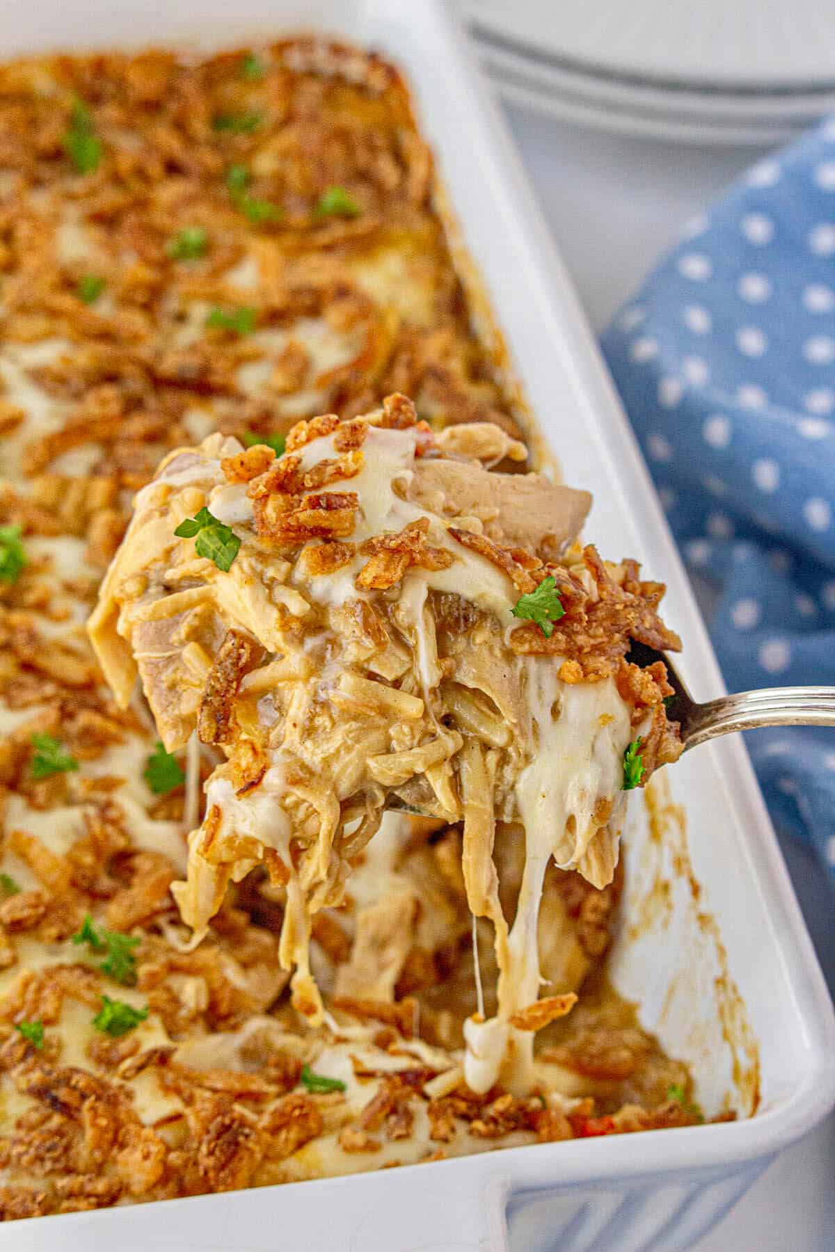 Chicken and Rice Casserole with French Onions in a baking dish. With a serving spoon dishing up a serving.