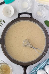 Gravy in a skillet with a whisk.
