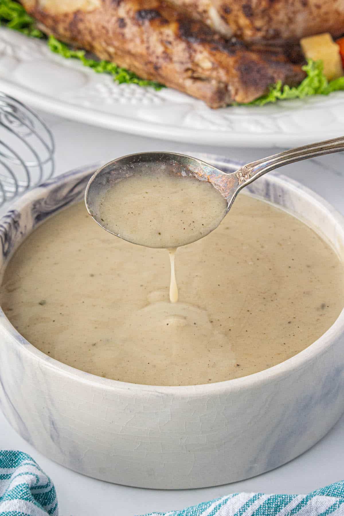 Rich turkey gravy in a bowl, with a spoon dipping into the gravy.