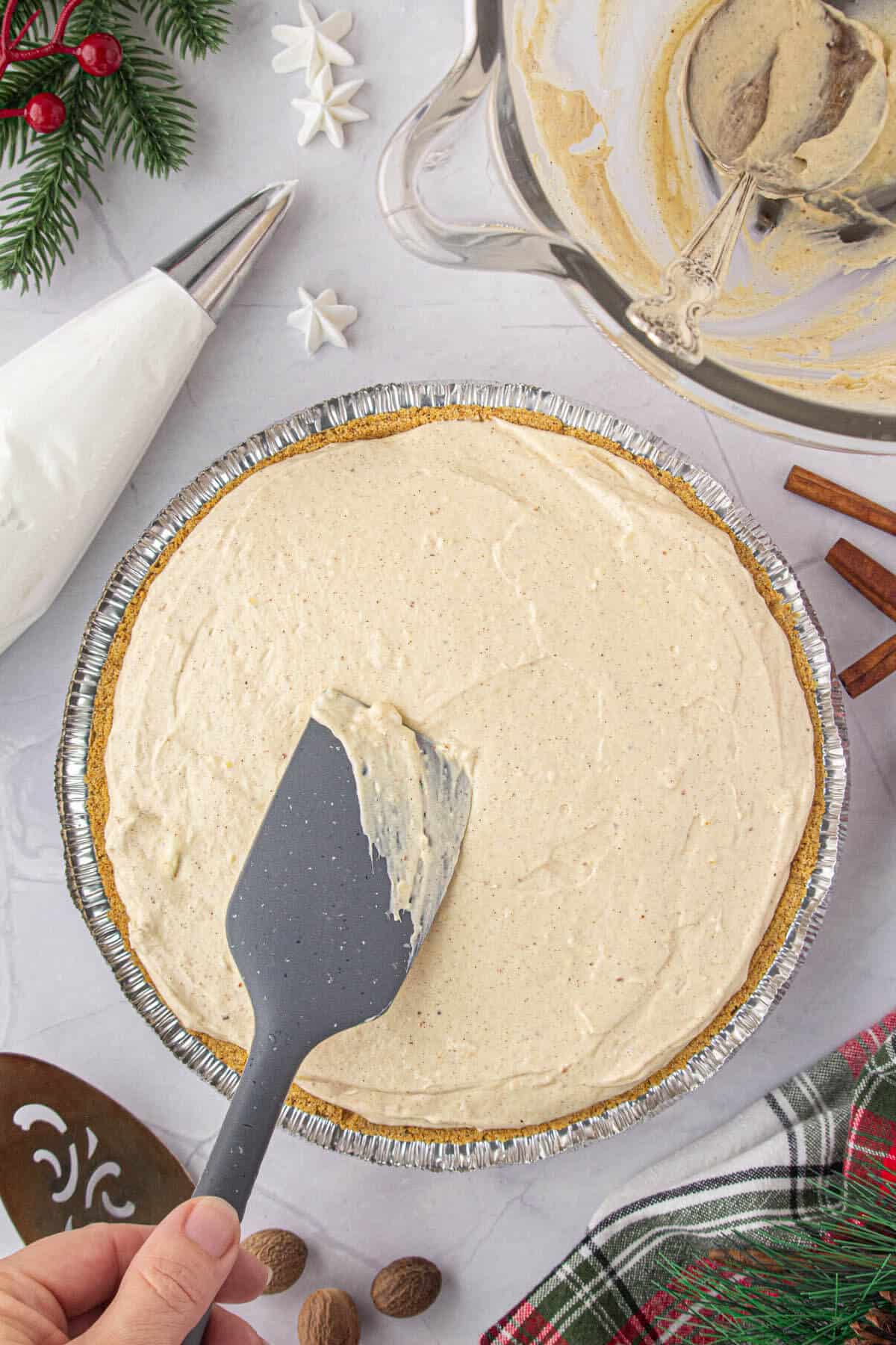 The pie filling has been spooned into a graham cracker crust and has been smoothed out with a spatula.