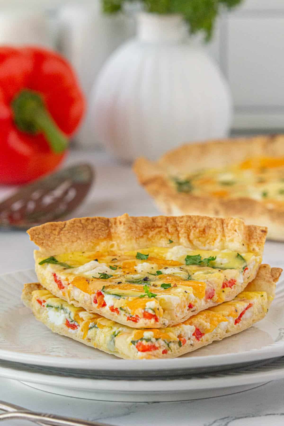 Sliced wedges of quiche with a tortilla crust stacked on a plate.