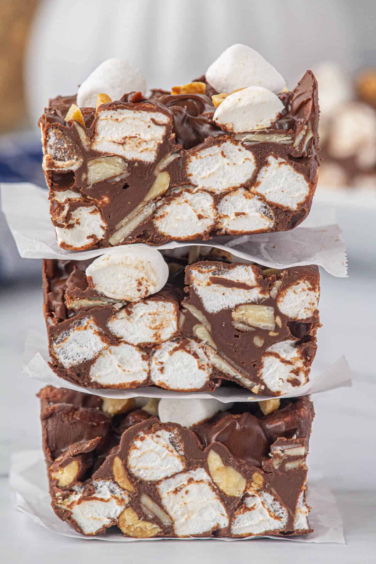 Three pieces of fudge stack on top of each other seperated by pieces of parchment paper.