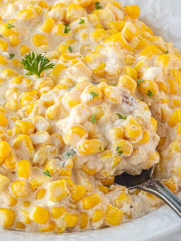 Creamed corn in a large bowl with a serving spoon.