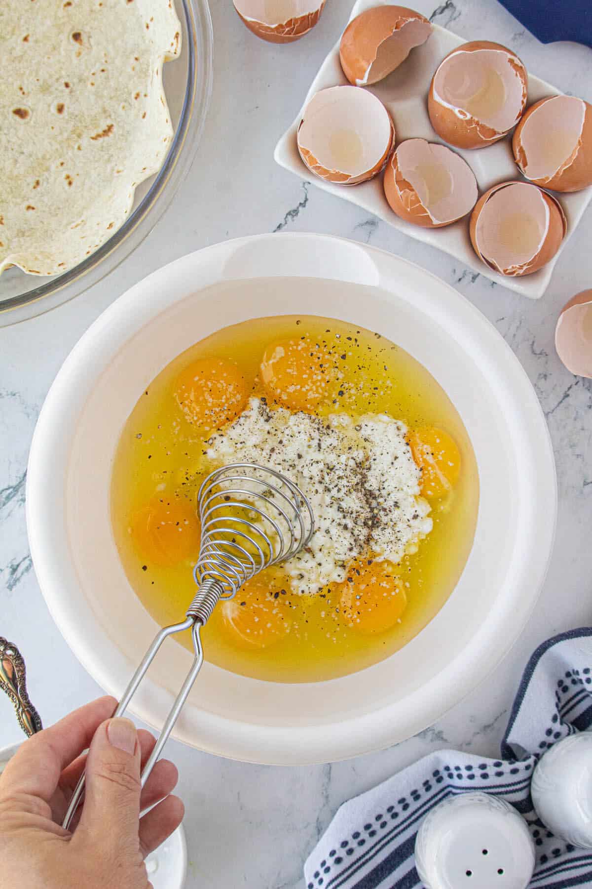 Eggs and cottage cheese in a bowl beaten beaten with a whisk.