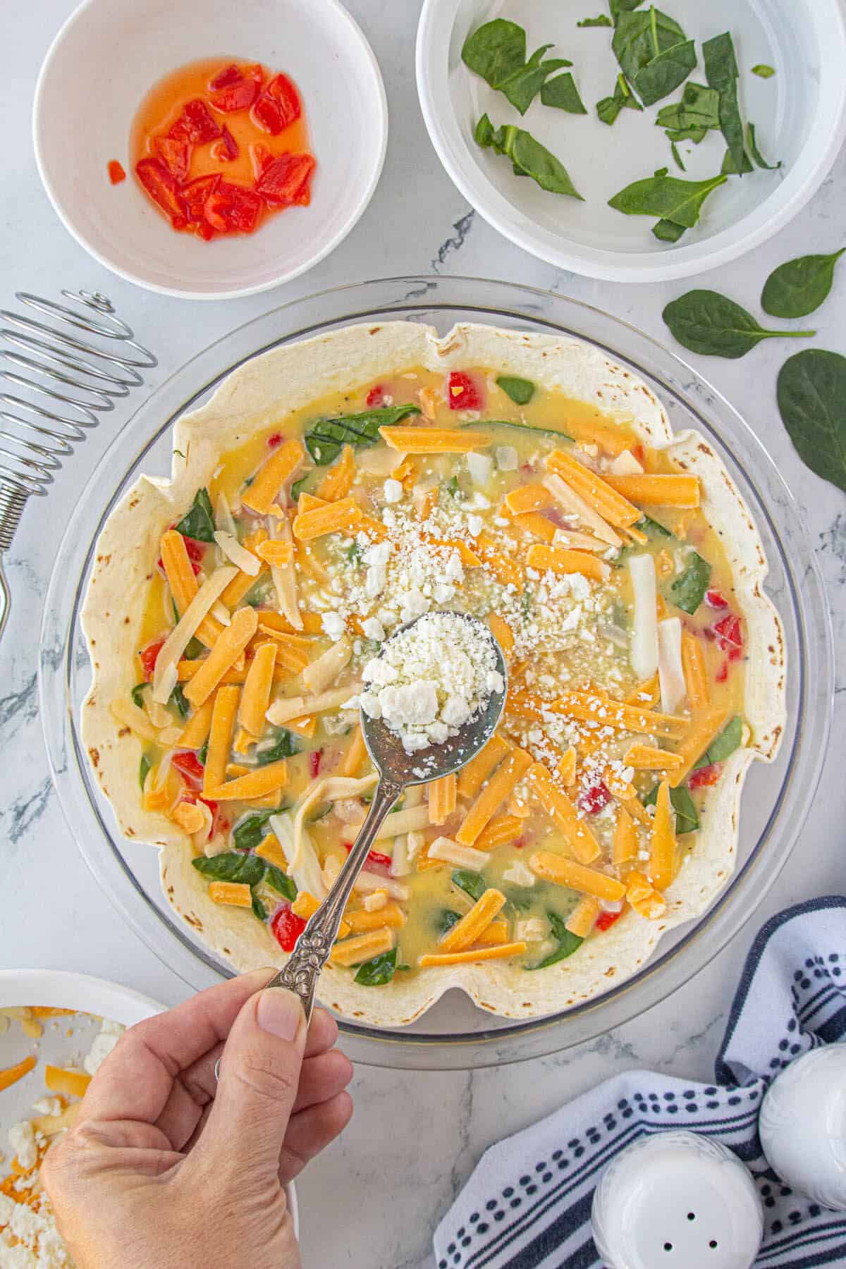 Tortilla quiche being topped with cheese before being baked.