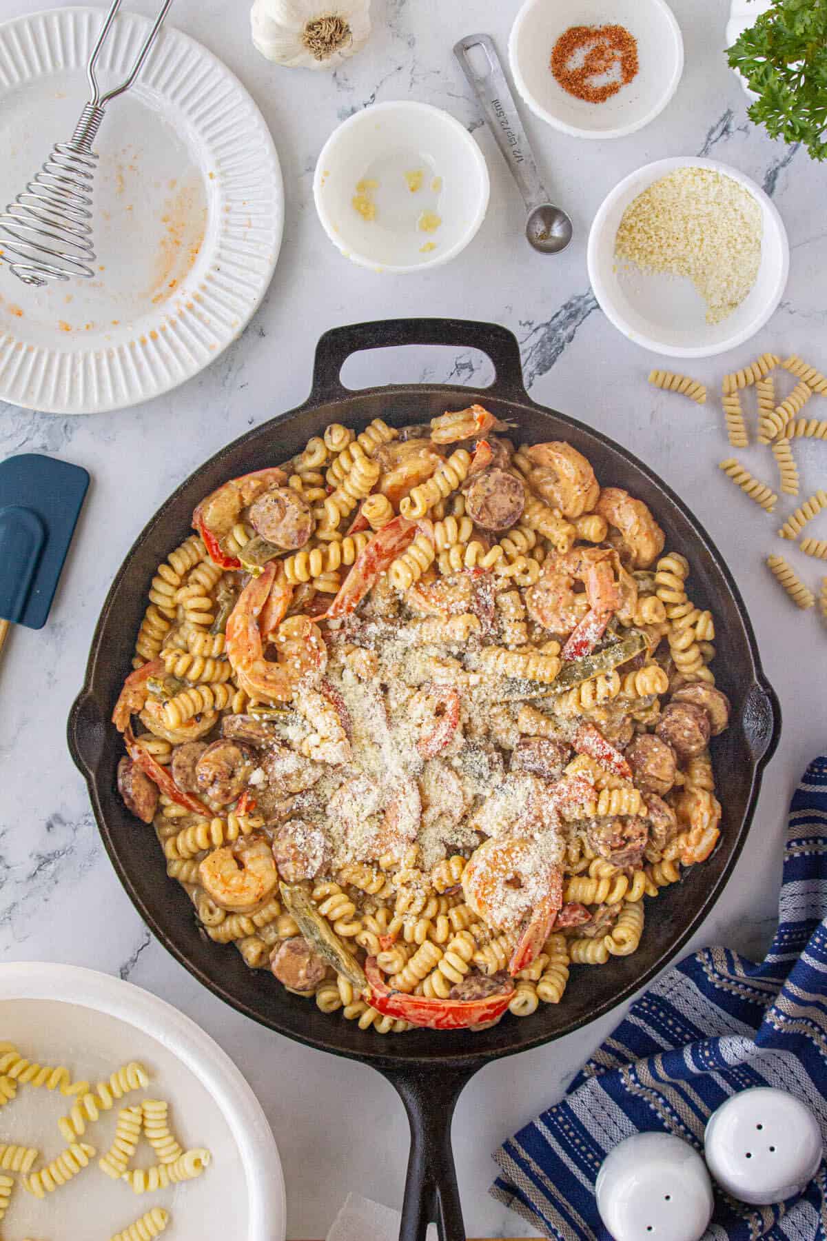 Cajun pasta in a skillet topped with a sprinkle parmesan cheese.