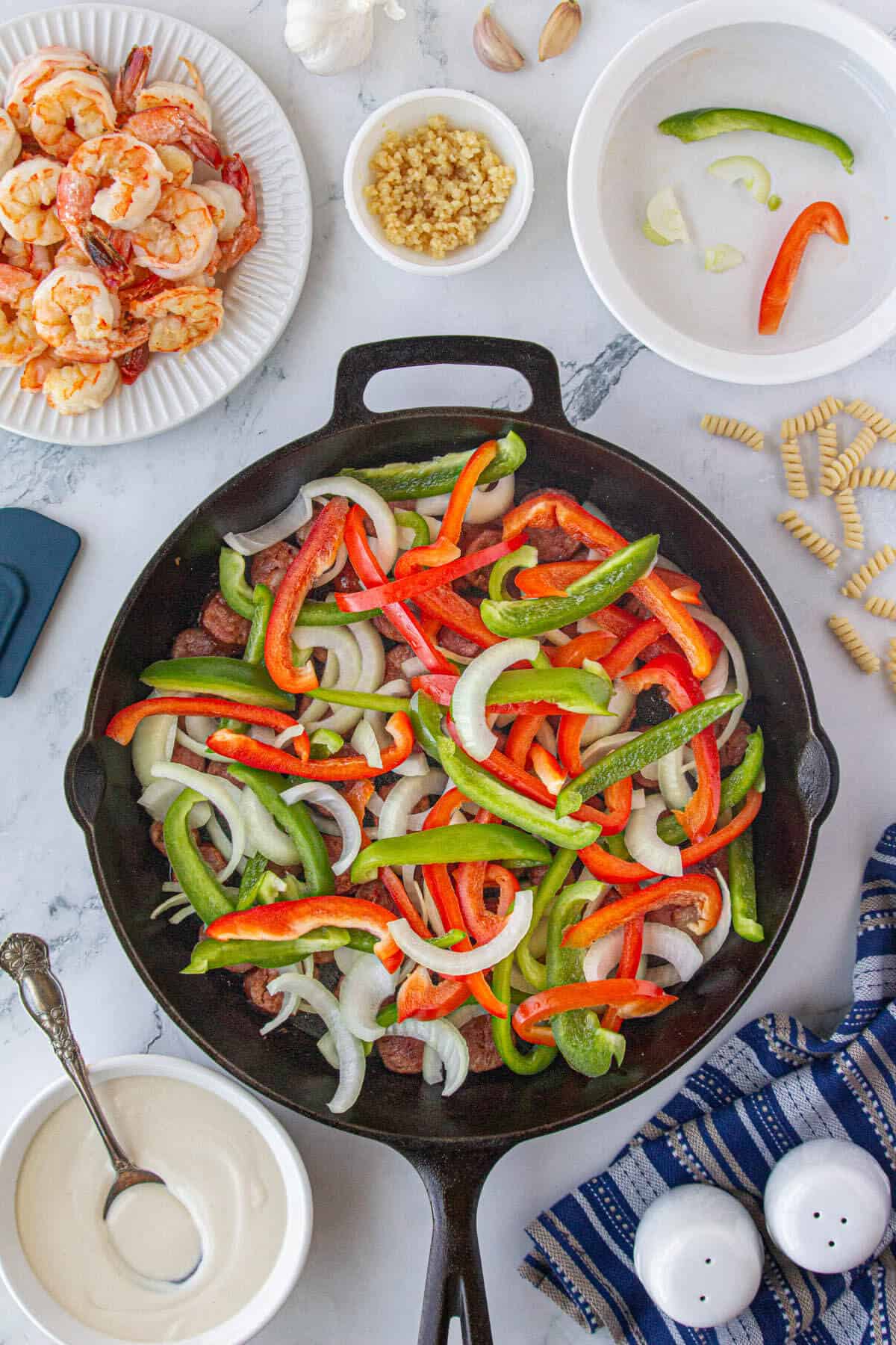 Sausage, sliced bell peppers and onions in a cast iron skillet.