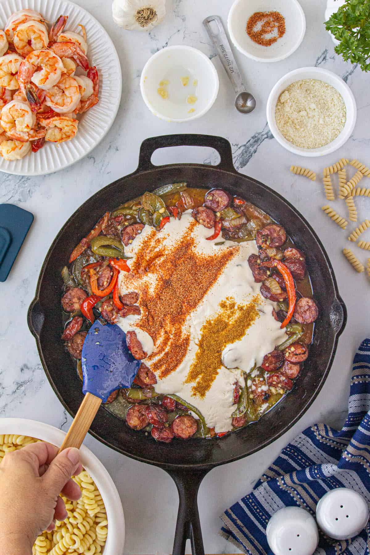 Alfredo sausage and cajun seasoning added to skillet filled with sauteed sausage, peppers and onions.