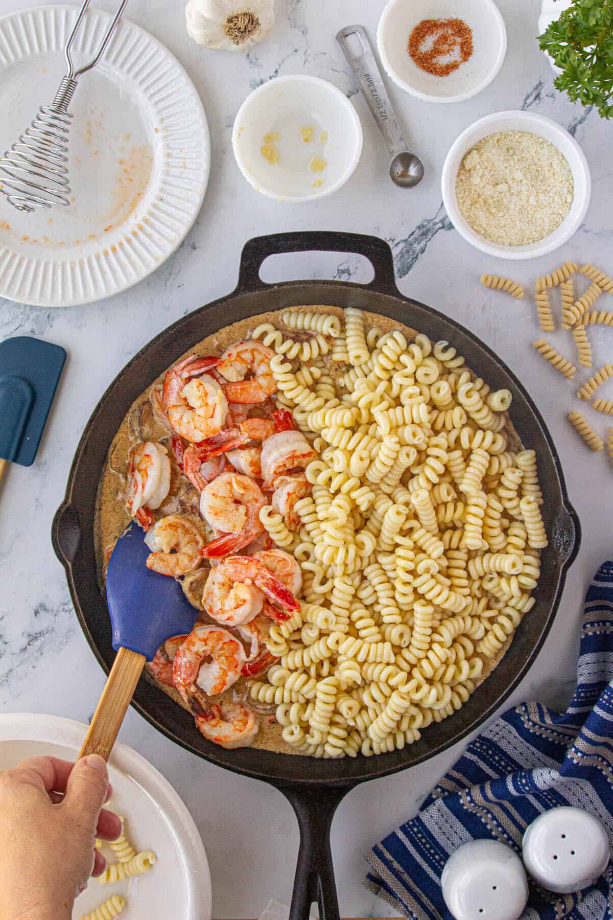 Shrimp and pasta added to a skillet filled cajun pasta sauce.