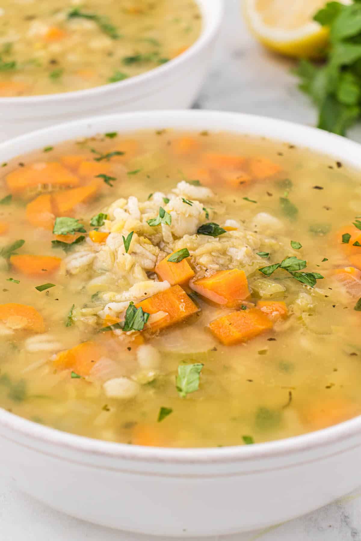 A white bowl filled with Barley and Lentil Soup.