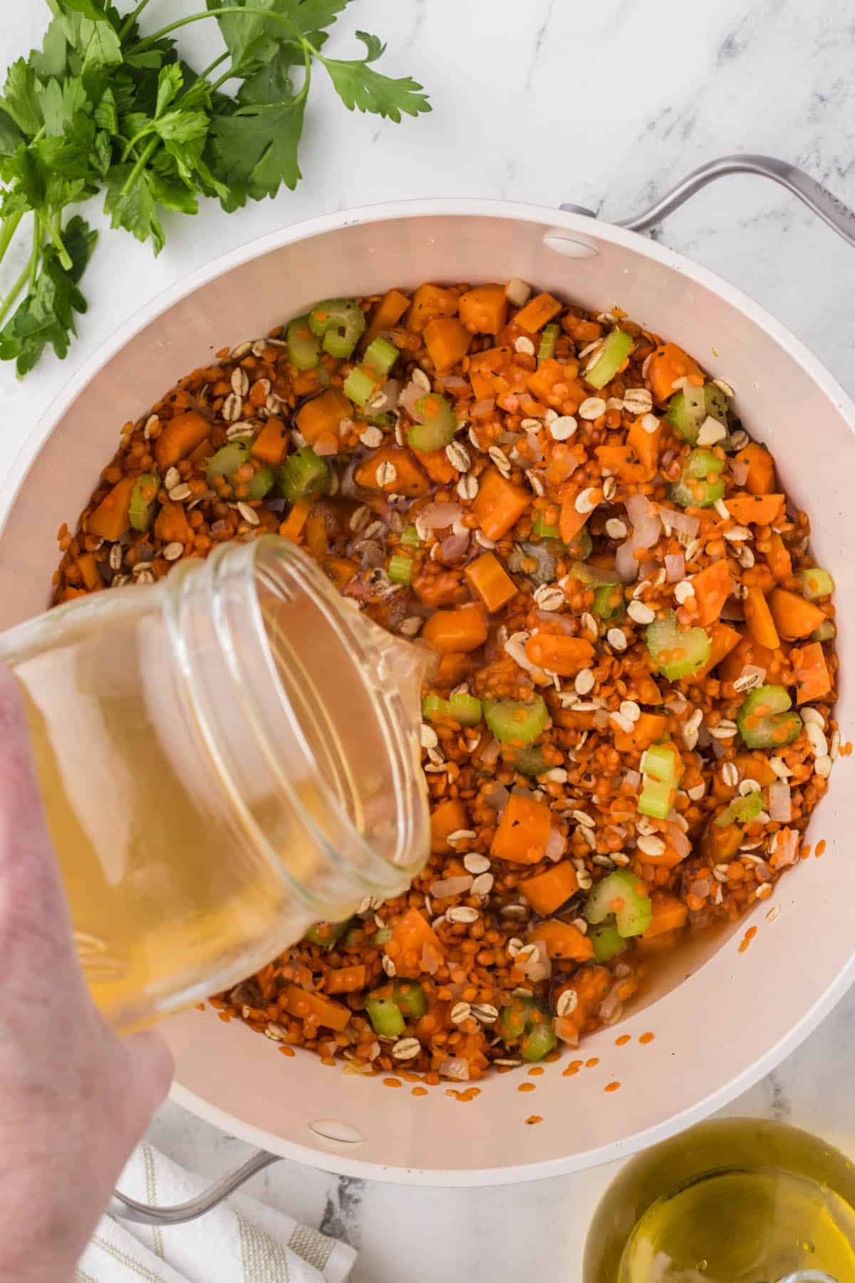 Stock added to lentils and barley in a soup pot.