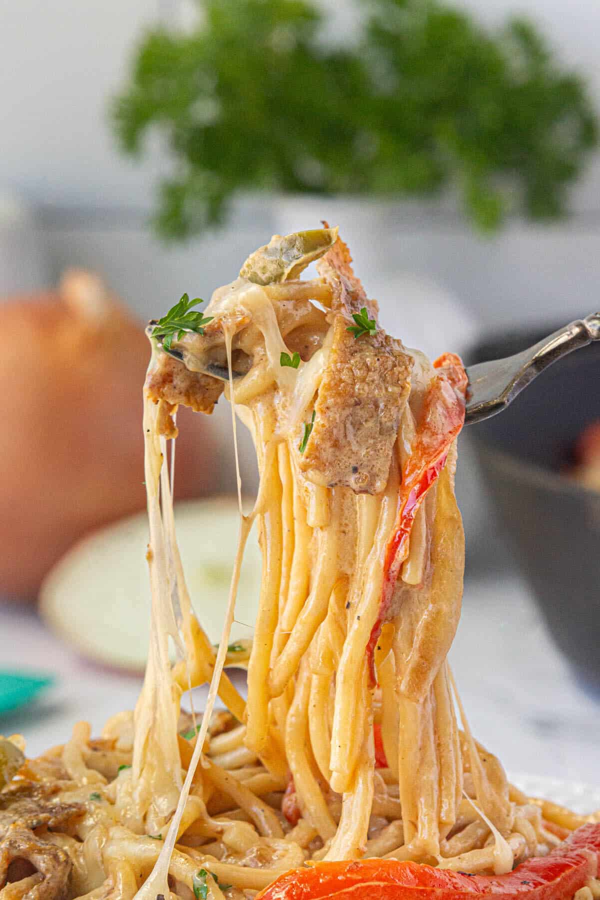 A fork pulling a serving of cheesy pasta from a plate.