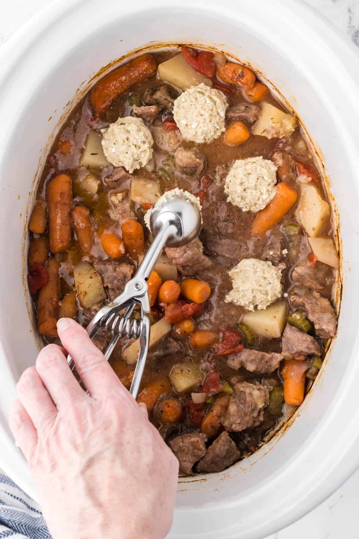 Dumplings added to the top of beef stew in a crockpot.