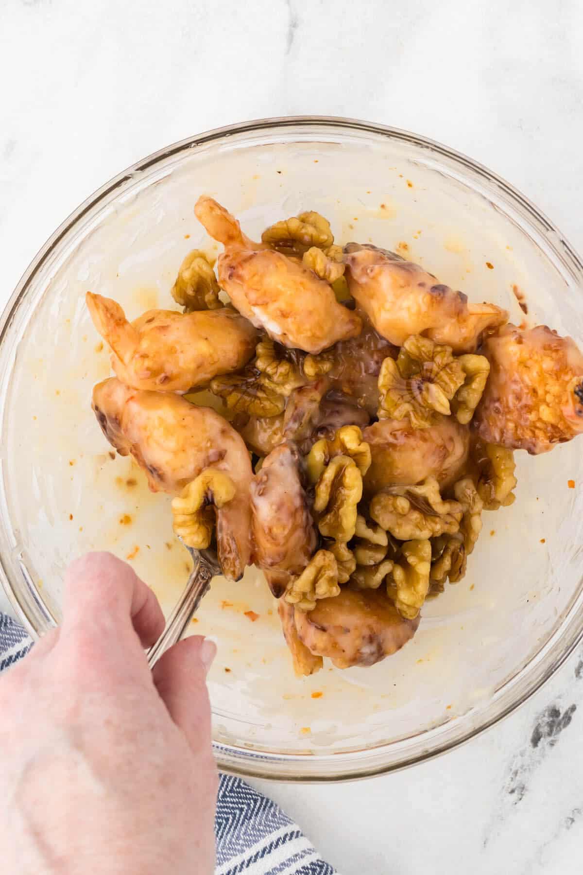 Coconut shrimp and candied walnuts being tossed in a sweet sauce.