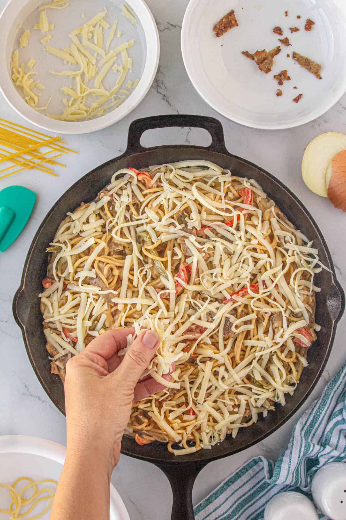 Shredded provolone cheese added to the top of the pasta dish before finishing under the broiler.