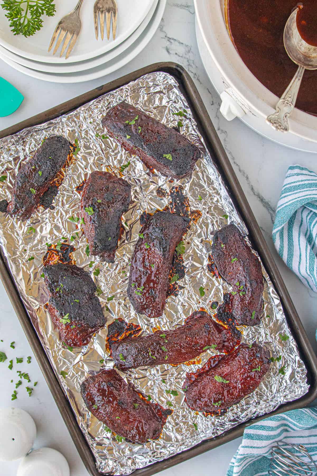 Pork ribs with carmalized sauce on a sheet pan lined with aluminum foil.