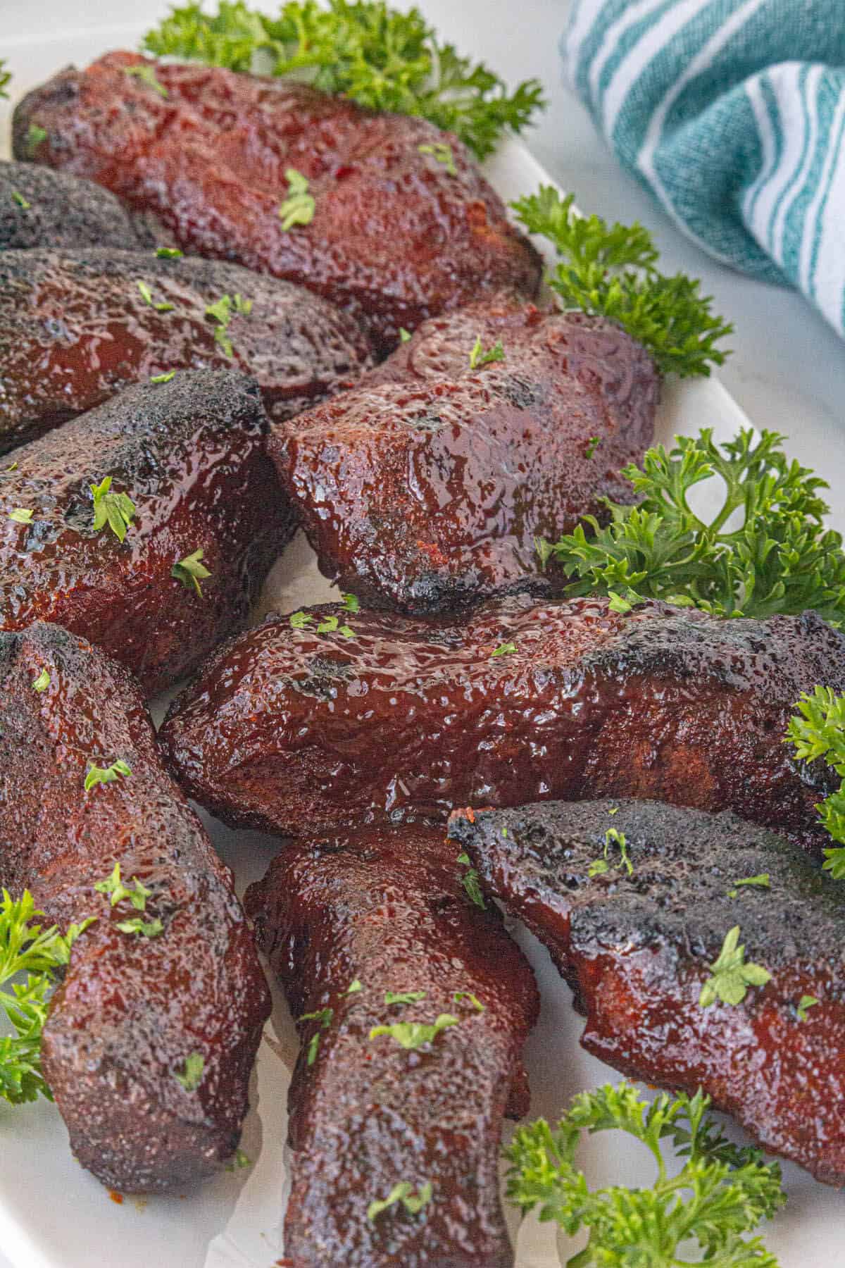 Cooked country style ribs on a platter, garnished with parsley.