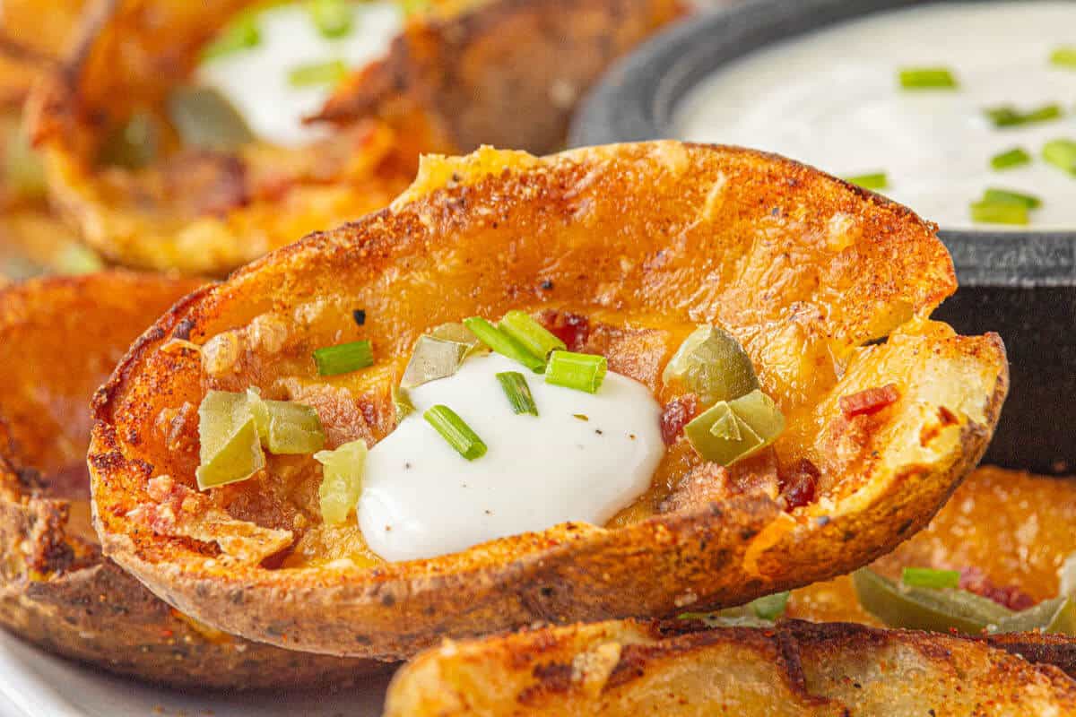 Crispy Air Fryer Potato Skins on a platter, topped with ranch dressing.