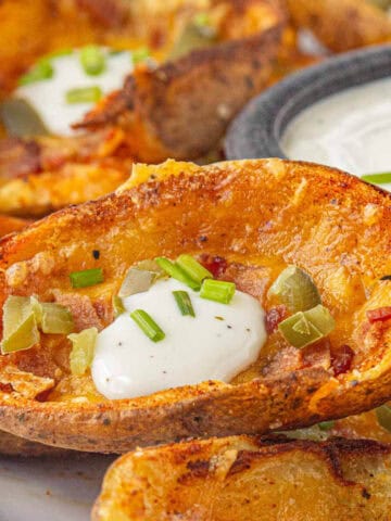 Crispy potato skins on a platter, with a ranch dipping sauce.