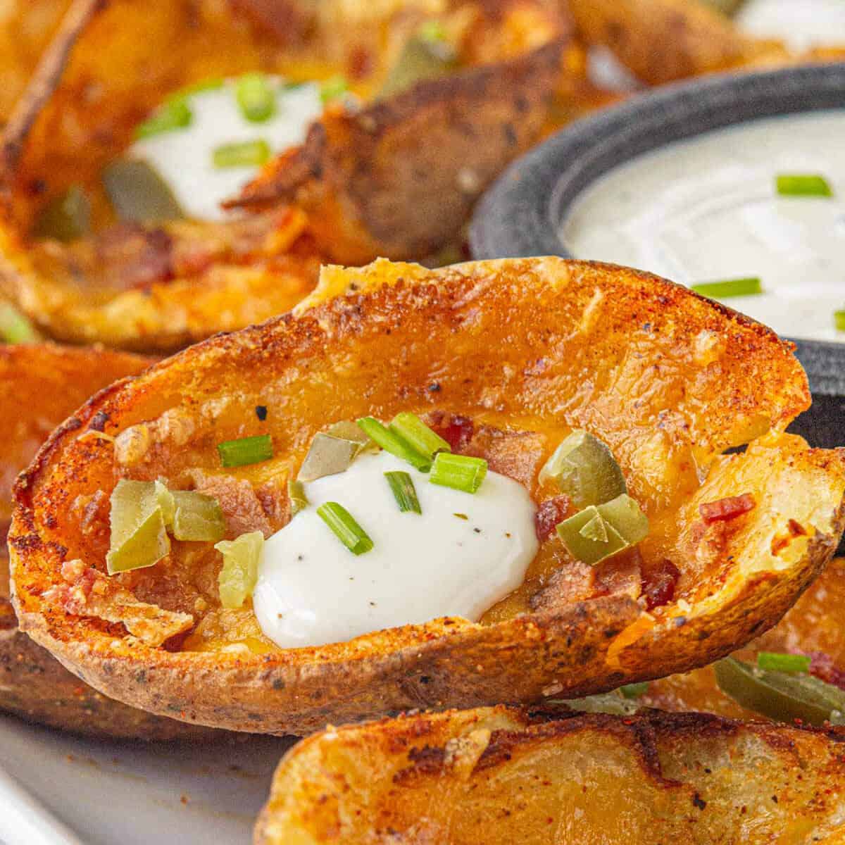 Crispy potato skins on a platter, with a ranch dipping sauce.