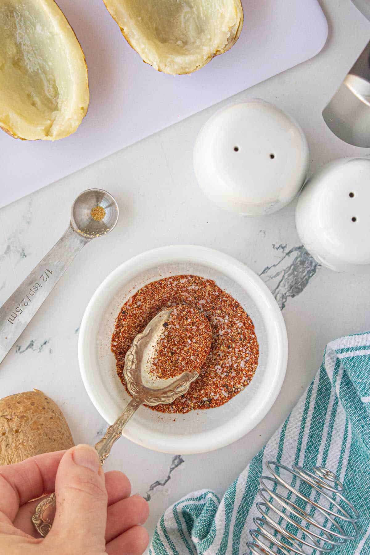 Spices mixed together in a bowl, with a serving spoon taking out a scoop.