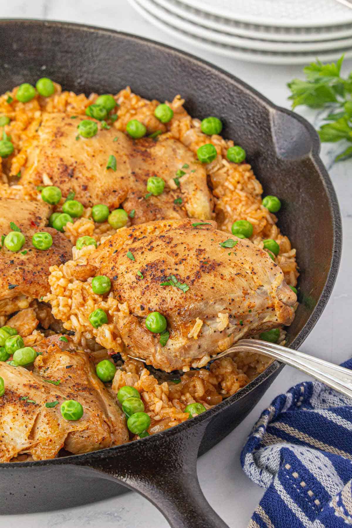 Stovetop Chicken and rice in a cast iron skillet, with a serving spoon.