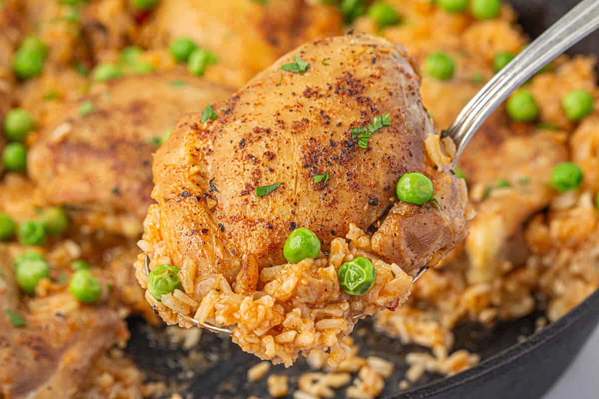 Stove top chicken and rice in a skillet, with a serving spoon.