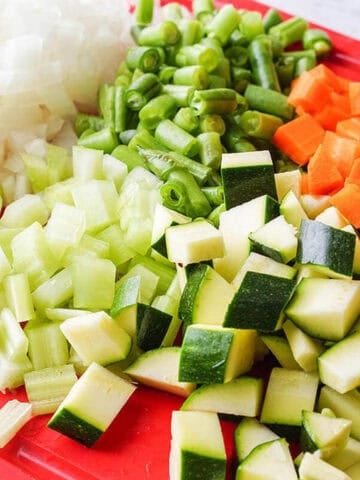 Chopped vegetables on a red cutting board.