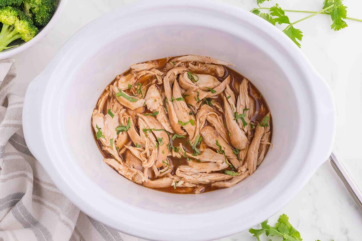 Honey garlic chicken in a white crockpot.