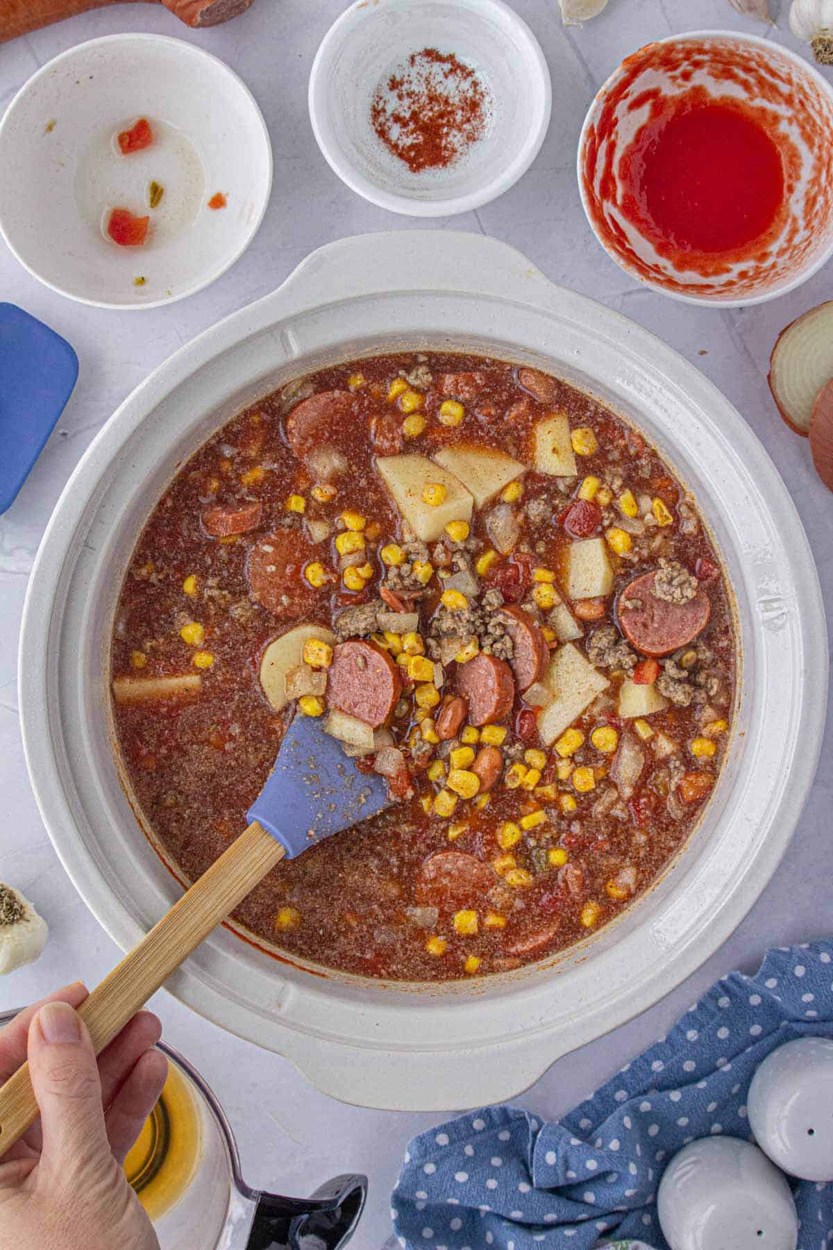 Stew ingredients in the crock pot being stirred together.