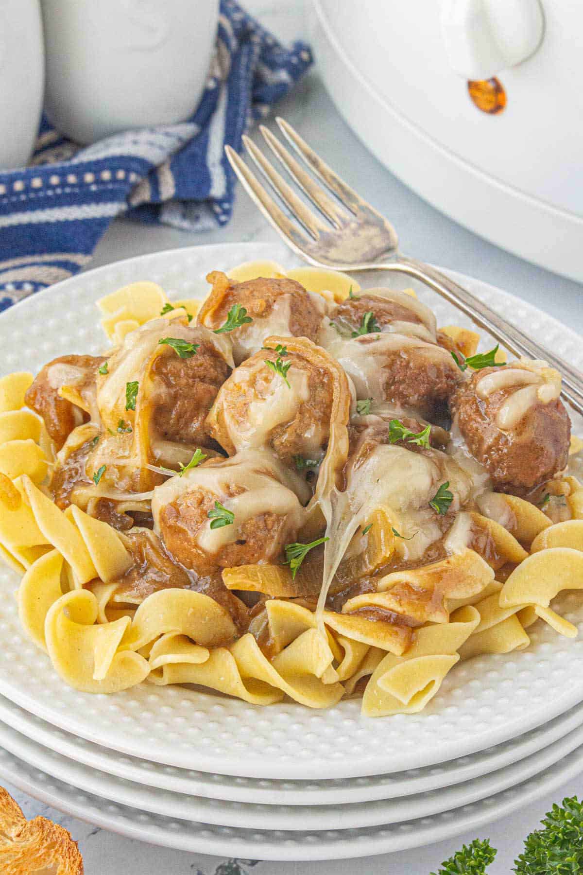 French onion meatballs served over a plate of egg noodles.