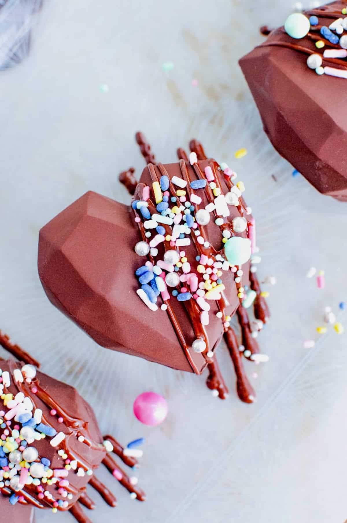 Heart shapped hot chocolate bombs decorated with pretty sprinkles.