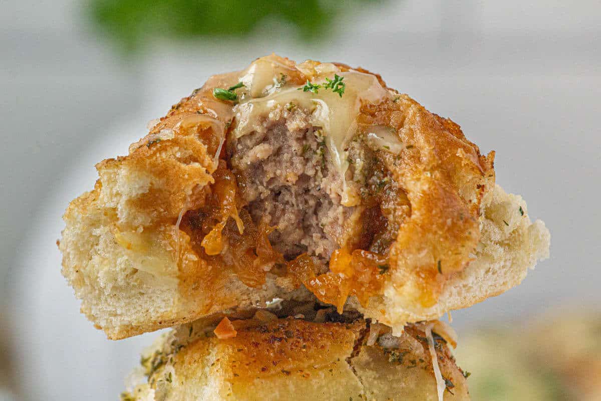 A meatball slider sandwich bitten in half.