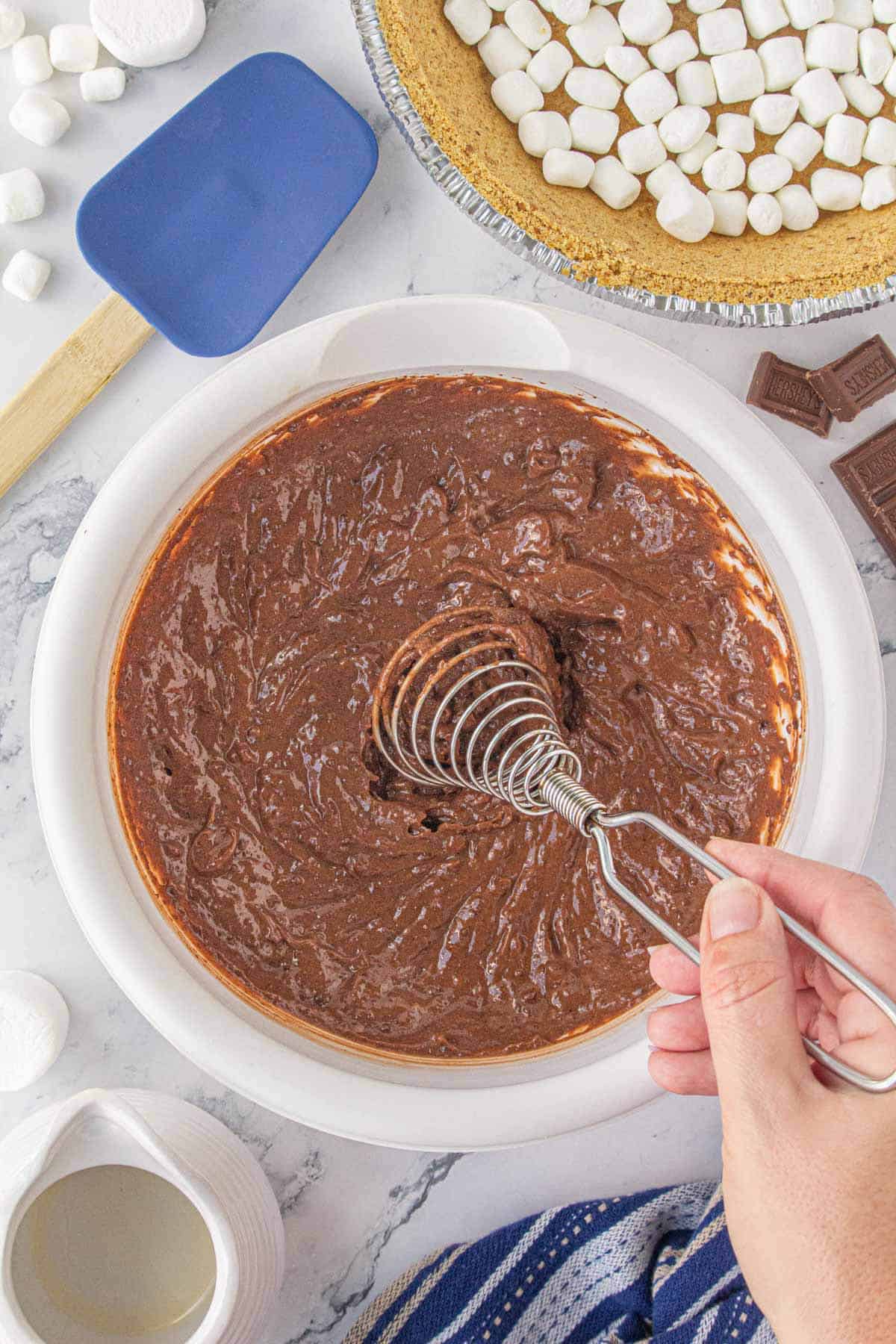 Chocolate pudding being whisked by hand in a large mixing bowl.