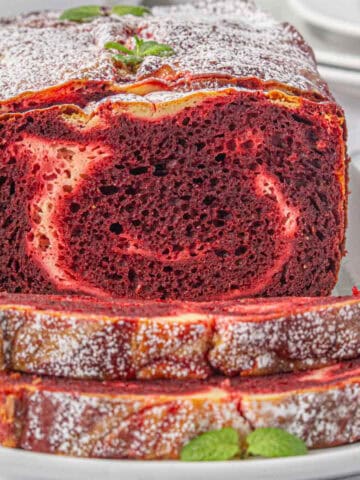 Red velvet loaf sliced on a platter.