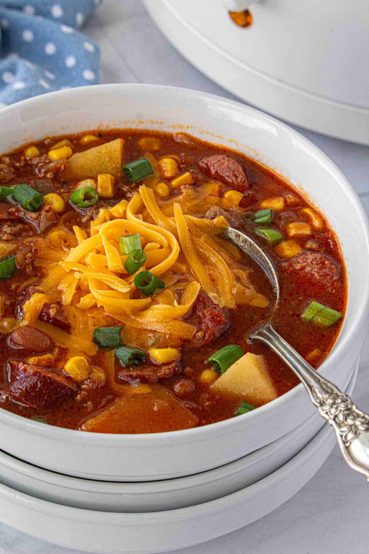 A soup bowl filled with crockpot cowboy stew. With a serving spoon.