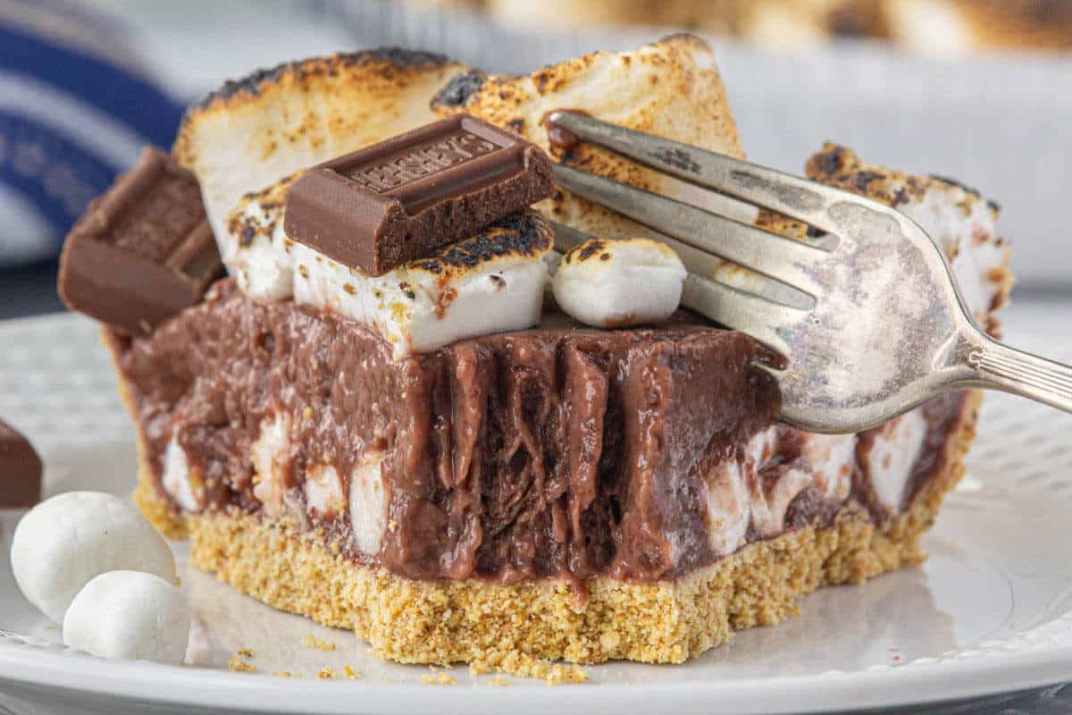 A slice of no bake s'mores pie on a plate with a fork.