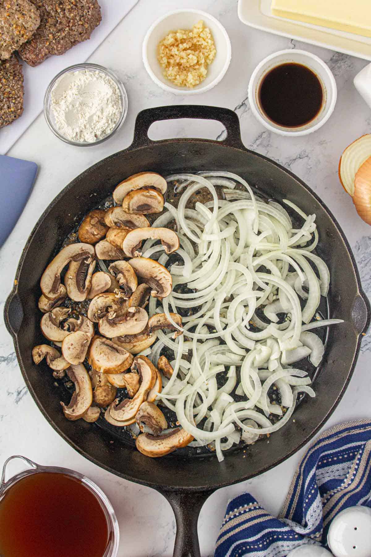 Onions and mushrooms sauteeing in a skillet.