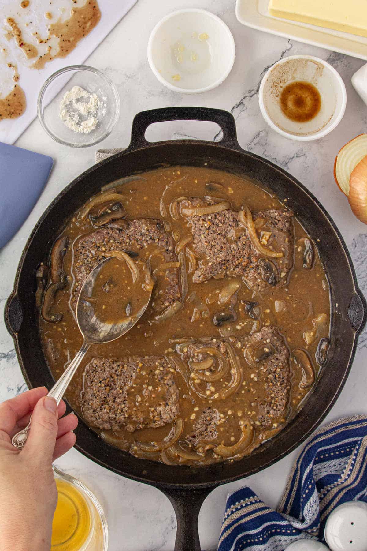 Steak in a skillet nestled into a rich brown gravy.