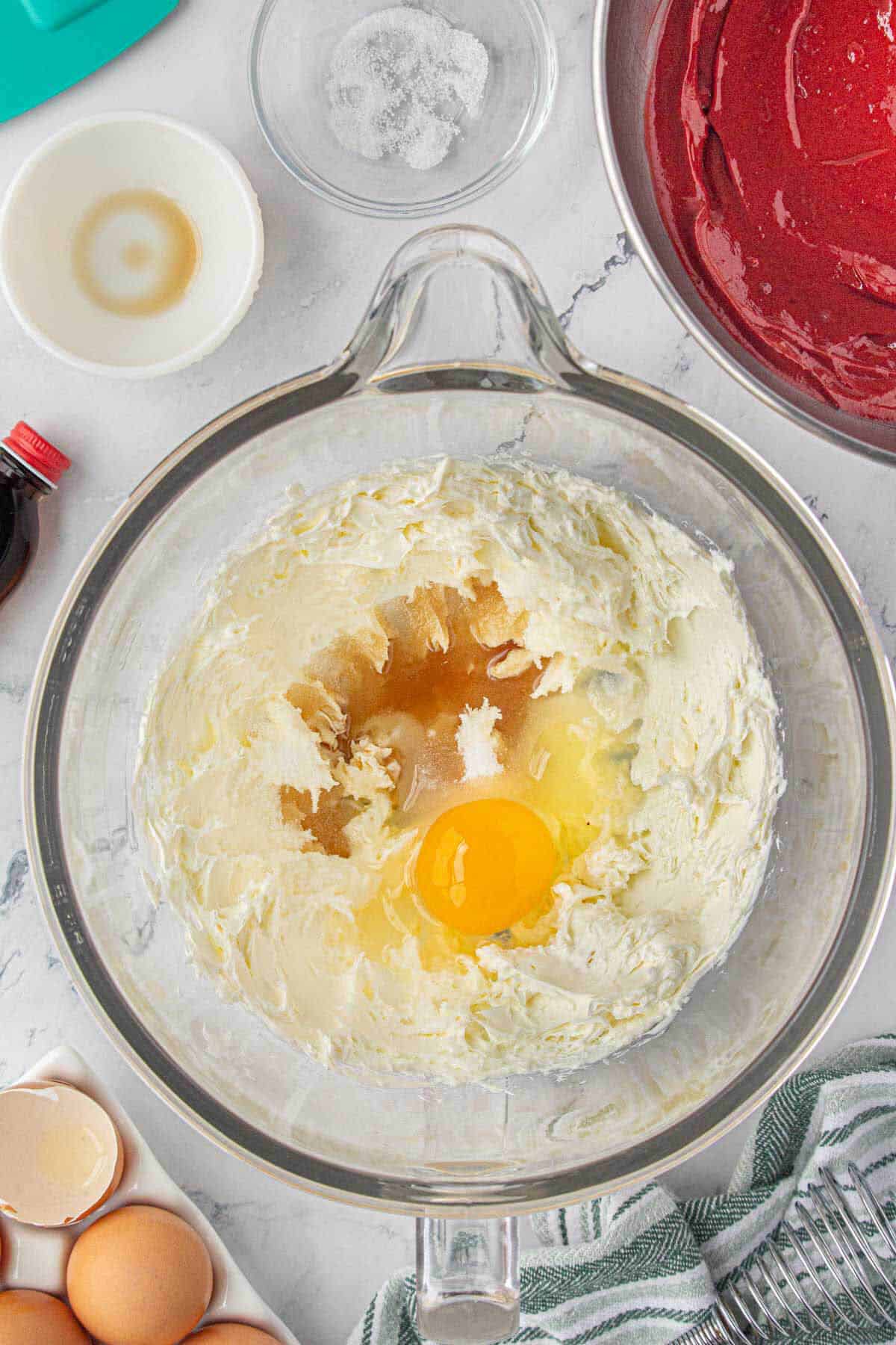 Eggs, sugar and vanilla added to a mixing bowl with cream cheese.