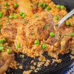 Seasoned cooked chicken thighs with rice in a skillet.