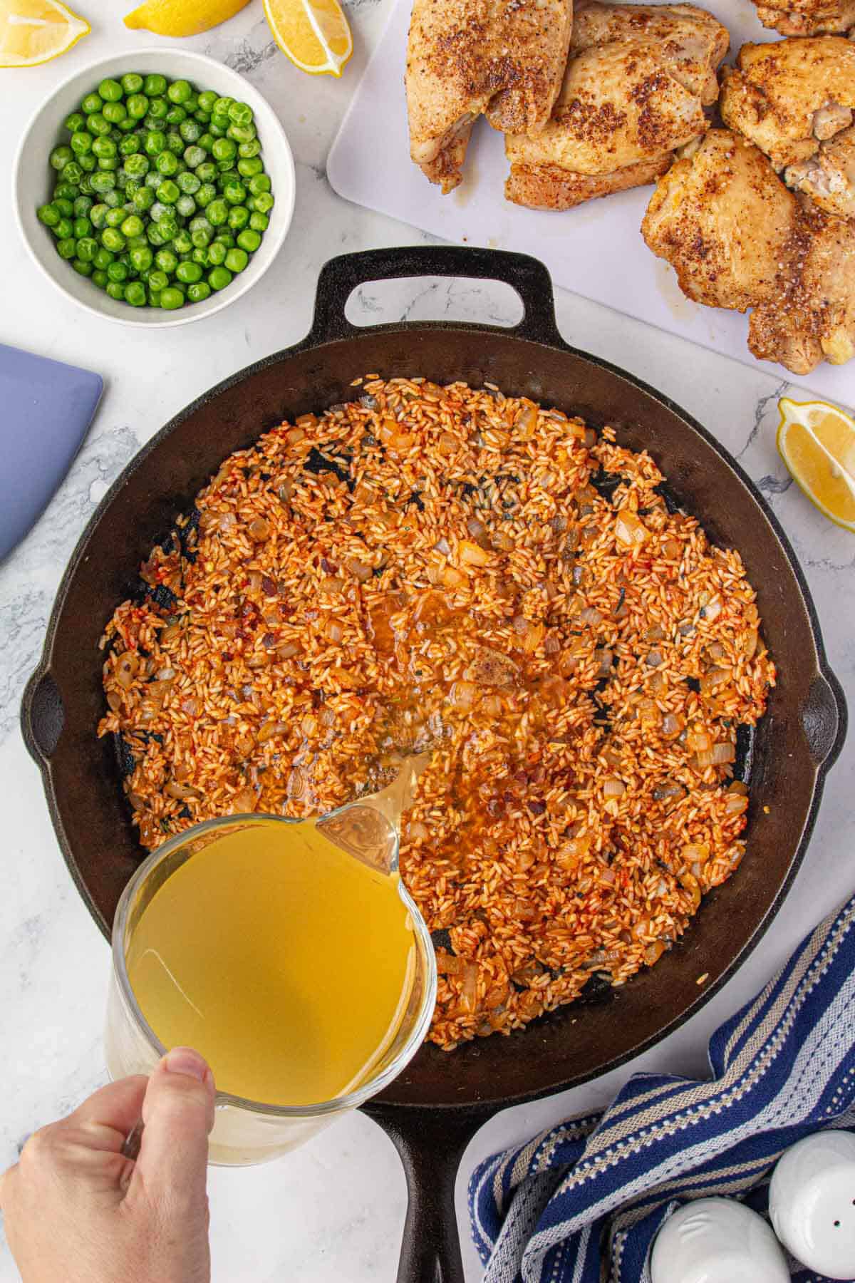 Chicken stock added to rice to cook in a skillet.